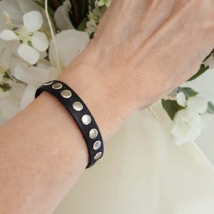 A woman wearing a black bracelet with silver dots.