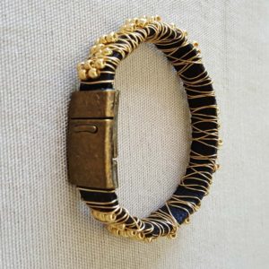 A bracelet with gold and black leather is shown.