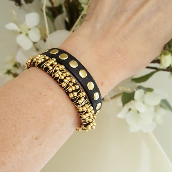 A woman wearing a black and gold bracelet.