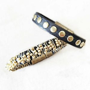 Two bracelets with gold and black beads on a white surface.