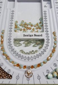 A white board with some beads and a picture of the design board