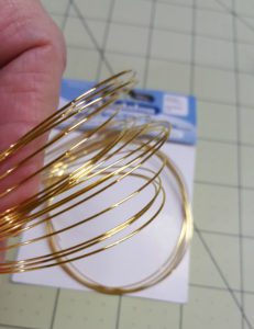 A person holding some gold wire in their hand.