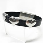 A black leather bracelet with silver hearts on it.