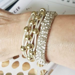 A woman wearing bracelets with gold beads and rhinestones.