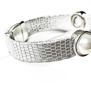 A silver bracelet with two large pearls on it.