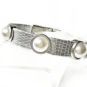 A silver bracelet with three pearls on it.