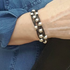 A person wearing a bracelet with pearls on it.