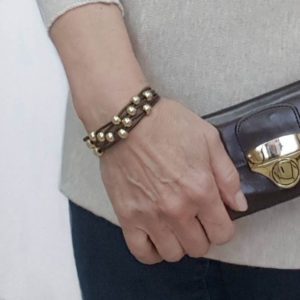 A woman wearing a bracelet and holding her purse.