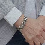 Gray leather bracelet with silver beads on wrist.