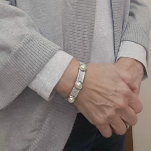 A person wearing a bracelet with a button on it.