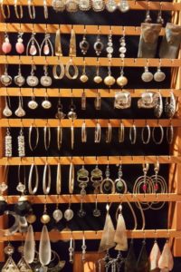 A wooden rack filled with lots of different types of earrings.
