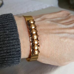 A person wearing a bracelet with gold beads on it.