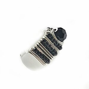 Side view adjustable silver ring hand beaded with black seed beads and faceted center stone.