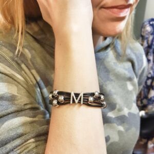 A woman wearing a bracelet with the letter m on it.