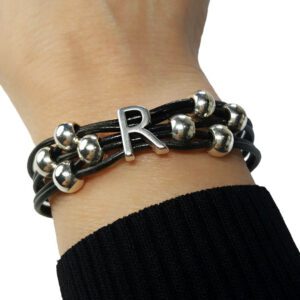 A person wearing a black leather bracelet with silver beads.