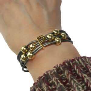 A person wearing a bracelet with gold beads and leather.