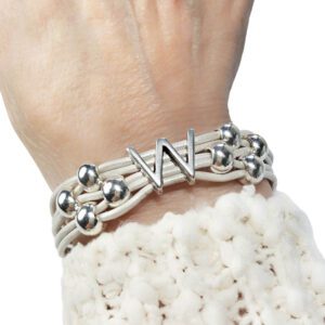 A person wearing a white bracelet with silver beads.