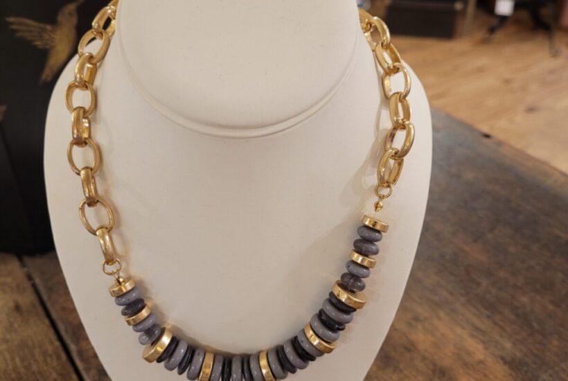A necklace is displayed on a white stand.