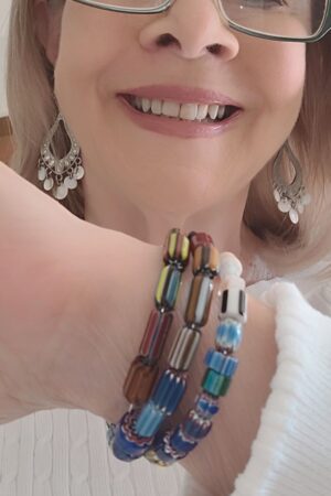 A woman wearing earrings and bracelets with her teeth.